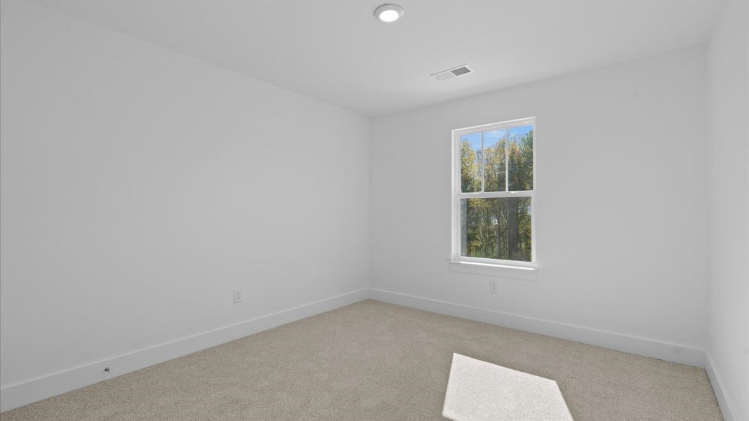 Elegant bedroom retreat featuring soft carpet and oversized windows that create a bright, welcoming space
