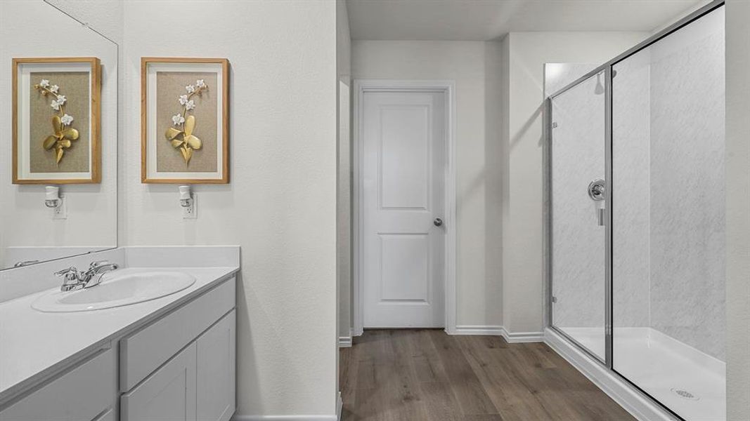 Bathroom featuring a vanity with a white countertop and a built-in sink, a large mirror, and a glass-enclosed shower