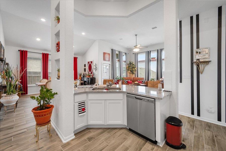 Kitchen with white cabinets, dishwasher, light stone counters, and wood finish floors Kitchen with white cabinets, dishwasher, light stone counters, and wood finish floors