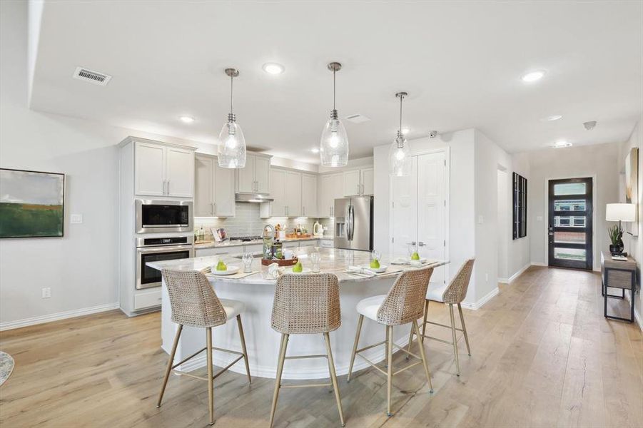Kitchen with a kitchen bar, light wood-style flooring, and light stone counters