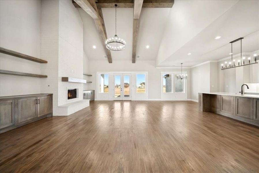 Unfurnished living room featuring dark hardwood / wood-style flooring, high vaulted ceiling, a chandelier, and beamed ceiling