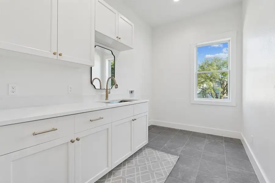 Laundry room with extensive storage and counter space, porcelain tile, utility sink, etc. This room is ALSO fully foam insulated.
