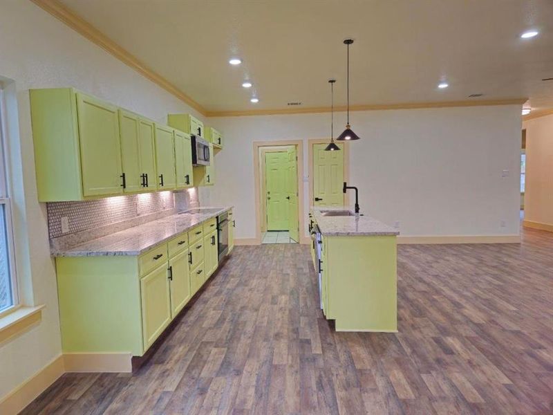 Kitchen with stainless steel appliances, hanging light fixtures, dark wood-type flooring, and sink