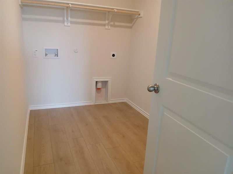 Dedicated laundry area featuring wood-finish flooring and white baseboards Dedicated laundry area featuring wood-finish flooring and white baseboards