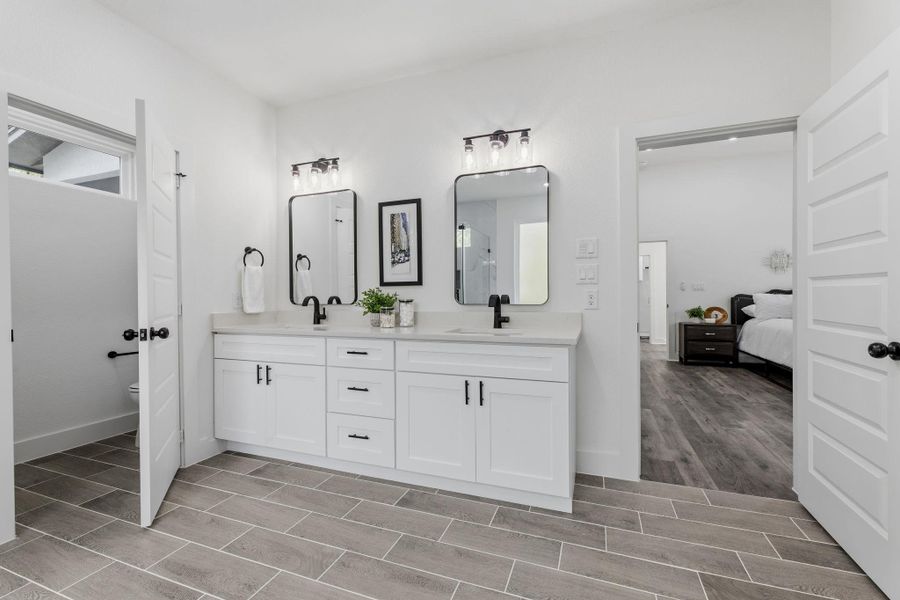 A well-appointed primary bathroom features a dual vanity, sleek black fixtures, and a private water closet.