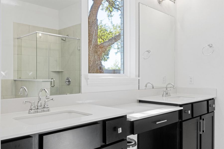 Full bath featuring double vanity, two vanities, and a shower stall Full bath featuring double vanity, two vanities, and a shower stall