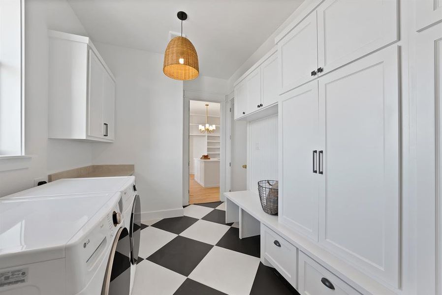 Washroom with dark floors, a chandelier, cabinet space, and washer and dryer