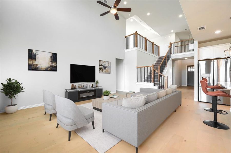 Living area with a high ceiling, light wood-type flooring, stairs, recessed lighting, and ceiling fan Living area with a high ceiling, light wood-type flooring, stairs, recessed lighting, and ceiling fan
