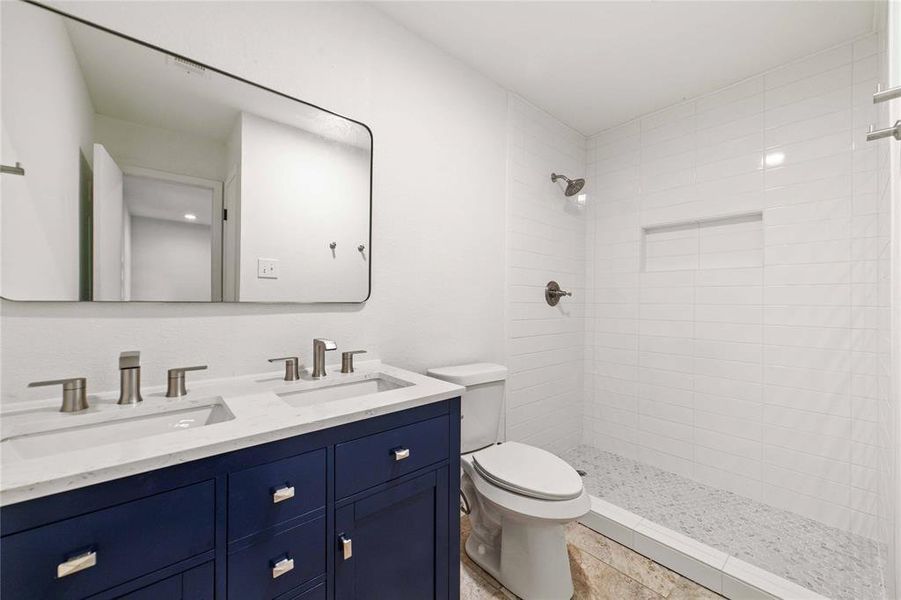 Full bathroom with tiled shower, a sink, toilet, and double vanity Full bathroom with tiled shower, a sink, toilet, and double vanity