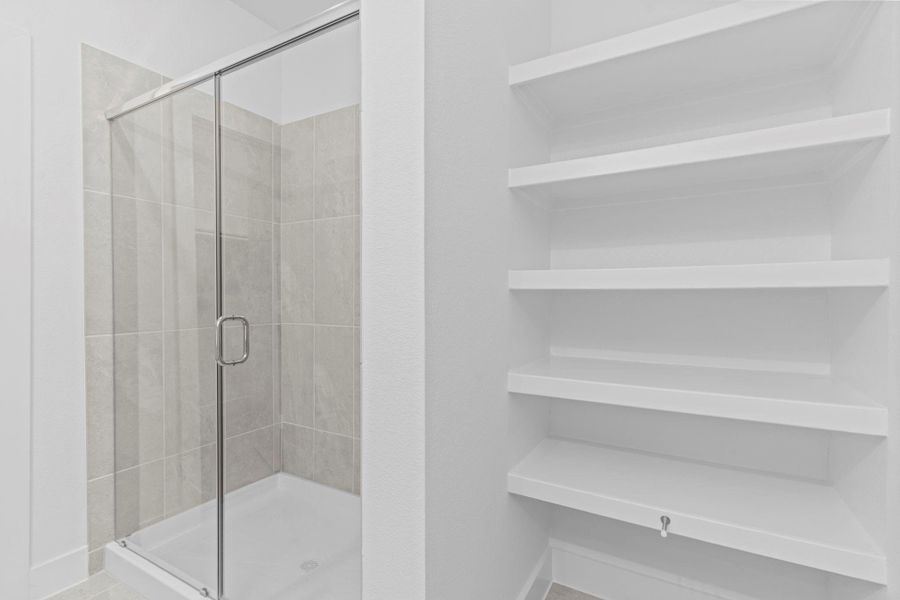 This view of the primary bathroom highlights the expansive super shower with elegant tile surround and a sleek frameless glass enclosure, perfectly paired with built-in shelving that adds smart storage for towels, toiletries, and décor. **Image Representative of Plan Only and May Vary as Built**. This view of the primary bathroom highlights the expansive super shower with elegant tile surround and a sleek frameless glass enclosure, perfectly paired with built-in shelving that adds smart storage for towels, toiletries, and décor. **Image Representative of Plan Only and May Vary as Built**.