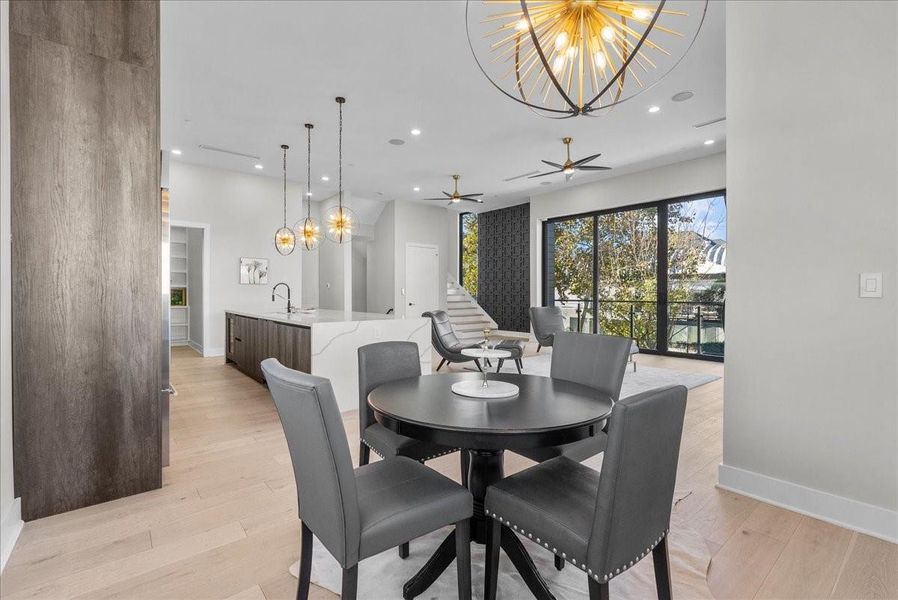 This modern open-concept living space features a sleek kitchen with an island, stylish pendant lighting, and a cozy dining area. Large windows and sliding doors lead to a balcony, allowing for abundant natural light and outdoor views. This modern open-concept living space features a sleek kitchen with an island, stylish pendant lighting, and a cozy dining area. Large windows and sliding doors lead to a balcony, allowing for abundant natural light and outdoor views.