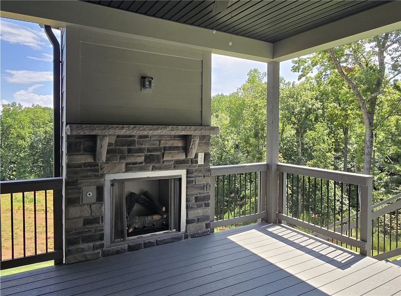 An inviting covered patio featuring a stone firepl