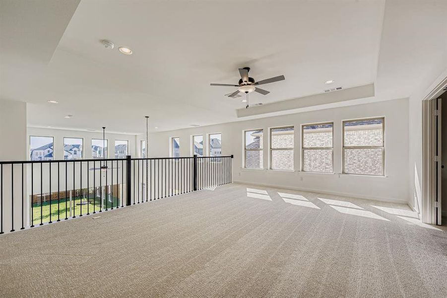 Unfurnished room with carpet floors, healthy amount of natural light, ceiling fan, recessed lighting, and a raised ceiling