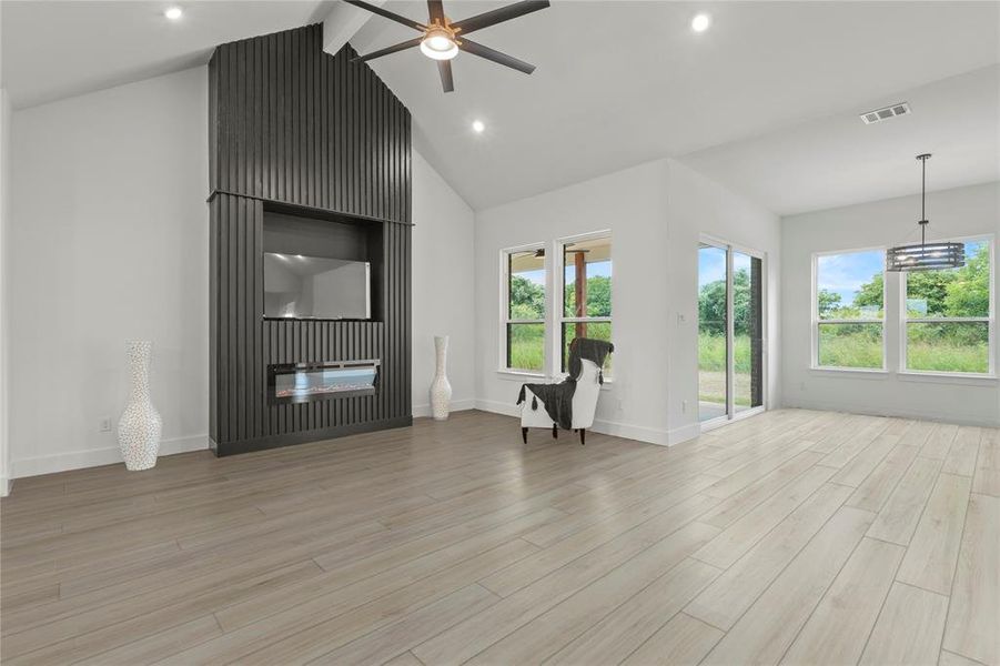 Unfurnished living room featuring ceiling fan, plenty of natural light, light wood-type flooring, recessed lighting, and high vaulted ceiling