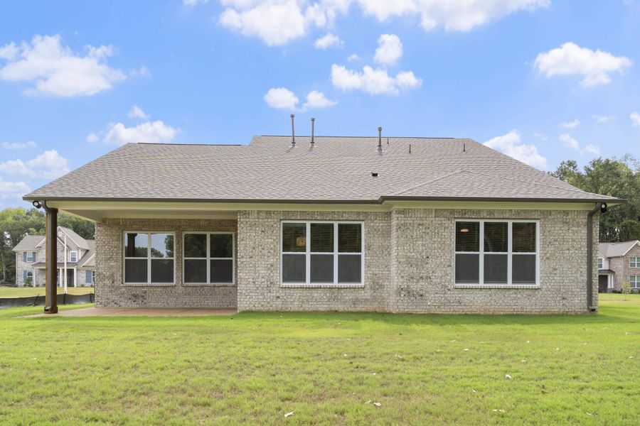 Brick exterior with a covered patio, multiple windows, and a shingle roof