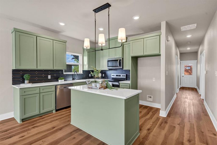 Kitchen with green cabinets, tasteful backsplash, stainless steel appliances, light wood-style floors, and pendant lighting Kitchen with green cabinets, tasteful backsplash, stainless steel appliances, light wood-style floors, and pendant lighting