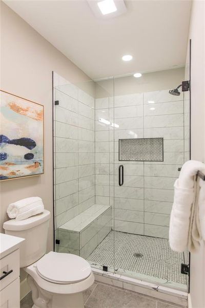 Bathroom featuring walk in shower, tile flooring, vanity, and toilet