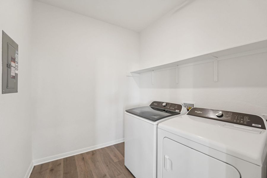 Laundry area with dark wood-style flooring, electric panel, and washer and clothes dryer