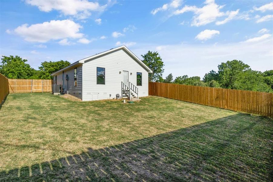 Rear view of house featuring entry steps and a fenced backyard