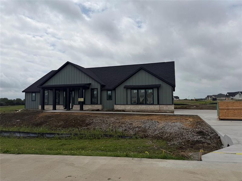 View of front of property with board and batten siding, covered porch, roof with shingles, and stone siding View of front of property with board and batten siding, covered porch, roof with shingles, and stone siding