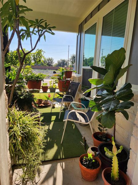 A tranquil covered front porch provides a welcoming entrance, adorned with lush potted plants and comfortable seating.