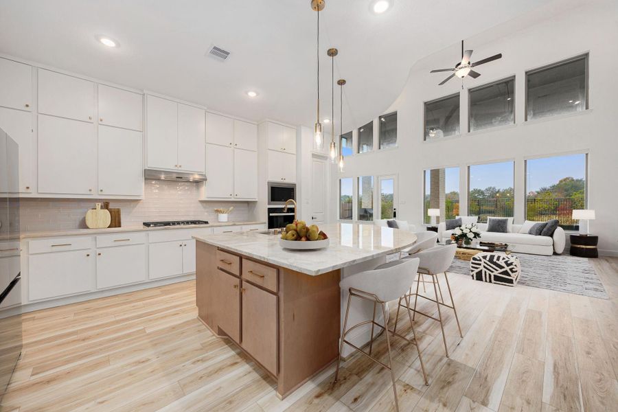 The expansive open-concept design features a spacious kitchen with oversized island, soaring ceilings, and walls of windows that fill the space with natural light.