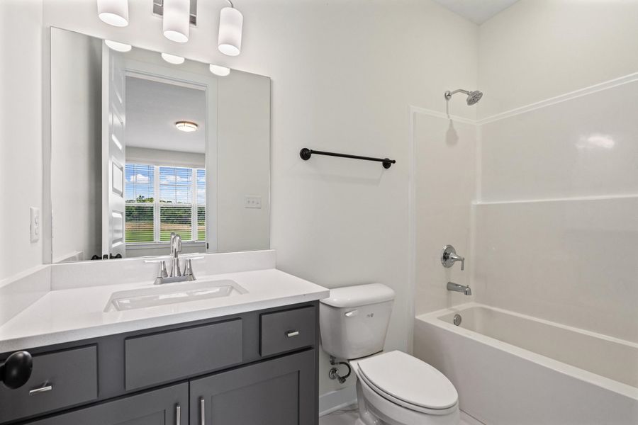 Bathroom featuring a single vanity with dark gray cabinetry, a white countertop, and an integrated sink Bathroom featuring a single vanity with dark gray cabinetry, a white countertop, and an integrated sink