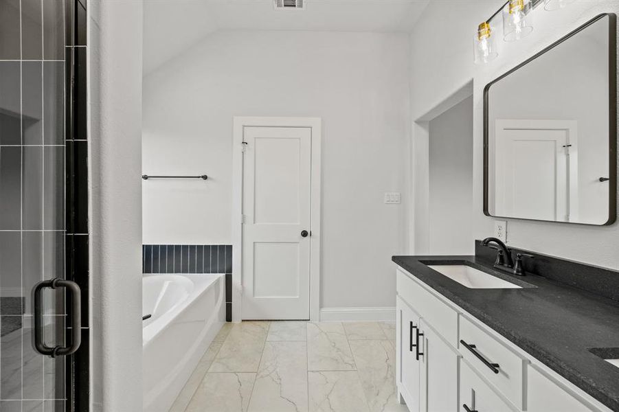 Bathroom with a bath, double vanity, light marble finish flooring, a shower stall, and vaulted ceiling