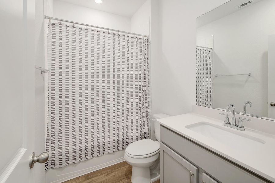 Bathroom featuring a light-colored vanity with an integrated sink, polished chrome faucet, and a large wall-mounted mirror Bathroom featuring a light-colored vanity with an integrated sink, polished chrome faucet, and a large wall-mounted mirror
