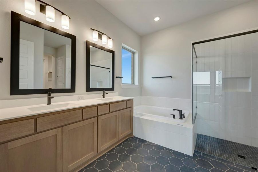 Bathroom with a bath, tiled shower, double vanity, and dark tile patterned flooring
