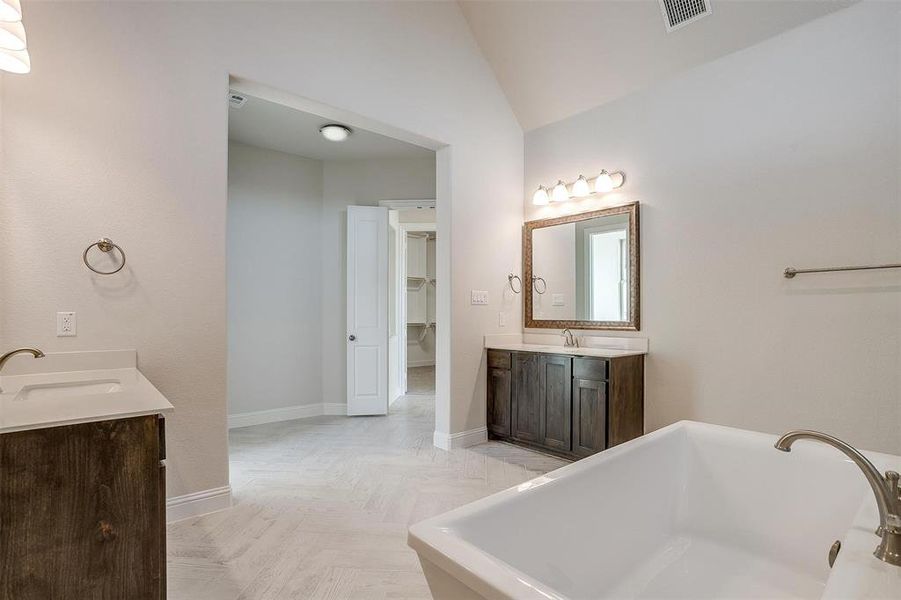 Bathroom with vanity, lofted ceiling, parquet floors, and a tub