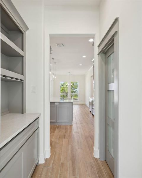 Hallway with light hardwood / wood-style flooring and a notable chandelier