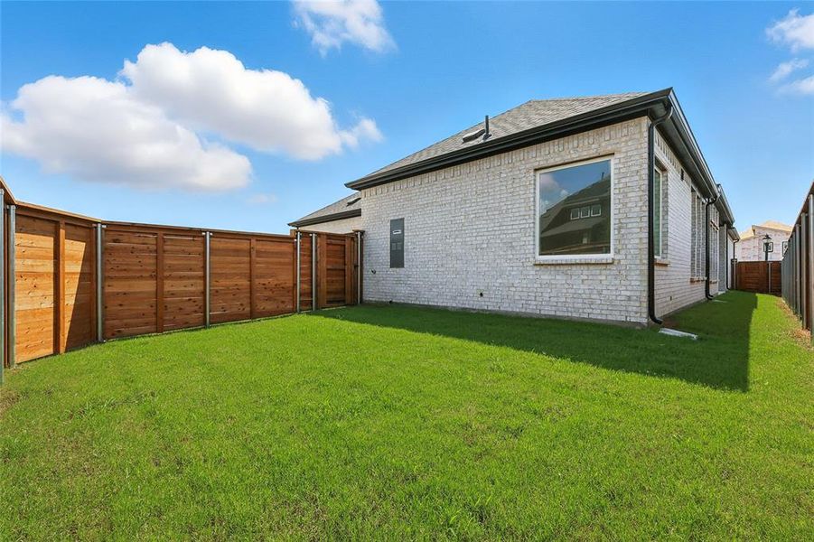 Rear view of property with brick siding, a fenced backyard, and a shingled roof