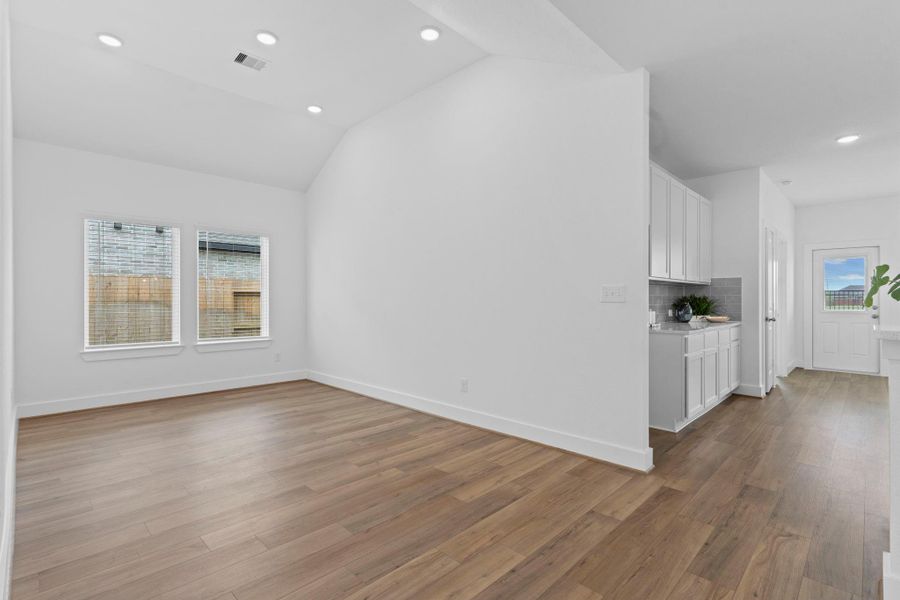 Elegant dining area features soaring ceilings, wood-look vinyl flooring, and a large rear-facing window that fills the space with natural light—perfect for formal dinners or casual family meals. **Image Representative of Plan Only and May Vary as Built**.