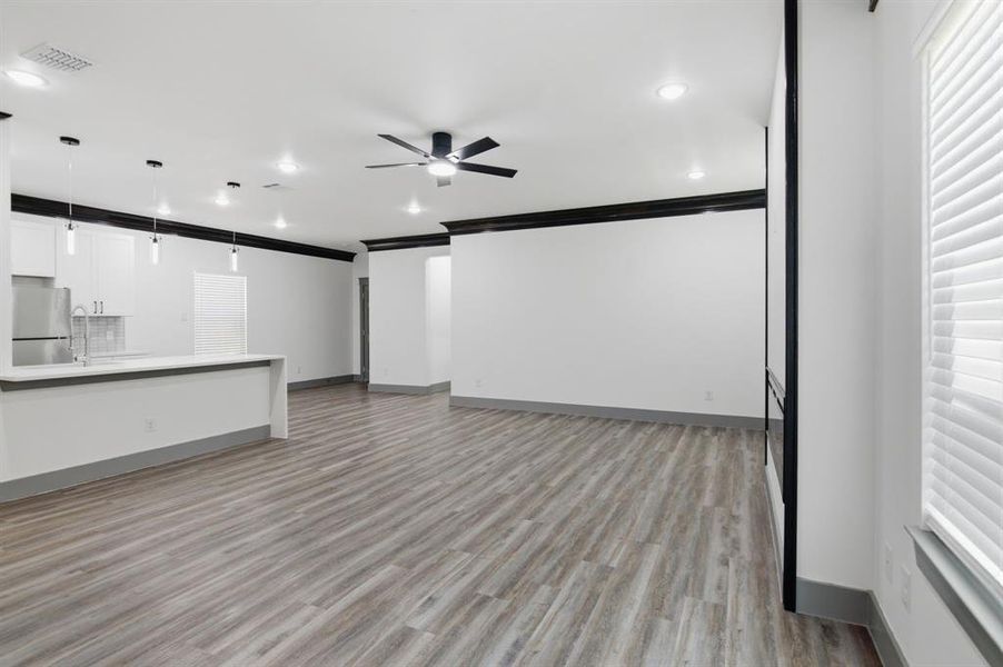 Open-concept living area with wood-finish flooring, a contemporary ceiling fan, and recessed lighting