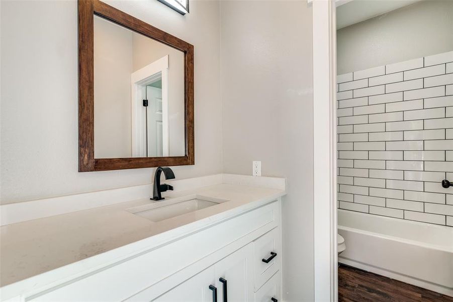 Full bathroom with hardwood / wood-style flooring, vanity, toilet, and tiled shower / bath combo