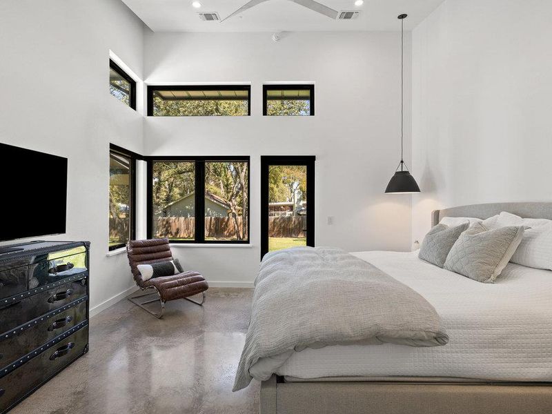 Bedroom featuring finished concrete flooring, a high ceiling, access to outside, and recessed lighting