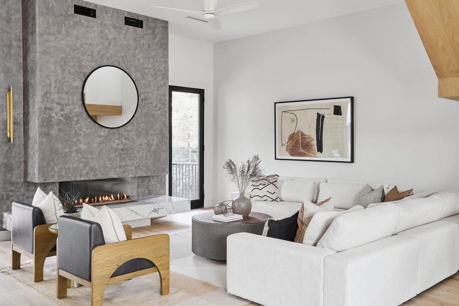 Living area featuring ceiling fan, a premium fireplace, and light wood-style floors Living area featuring ceiling fan, a premium fireplace, and light wood-style floors