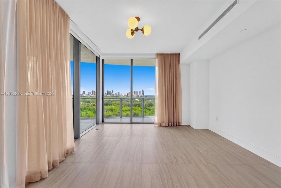 Floor-to-ceiling glass walls, wood-finish tile flooring, three-globe brass finish light fixture, recessed ceiling detail, and exterior balcony