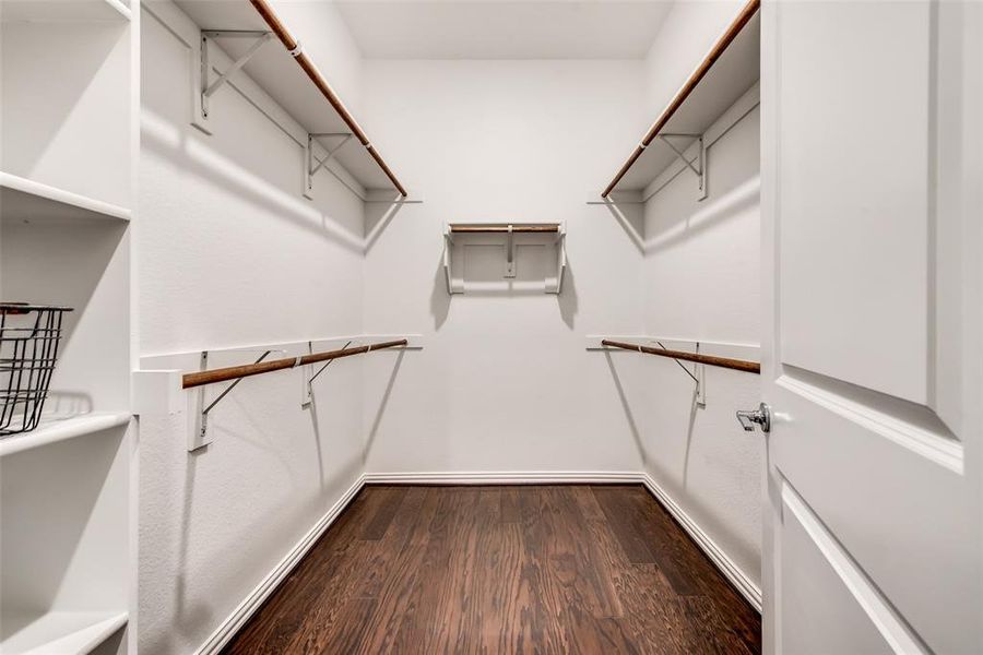 Walk in closet with dark wood-style floors