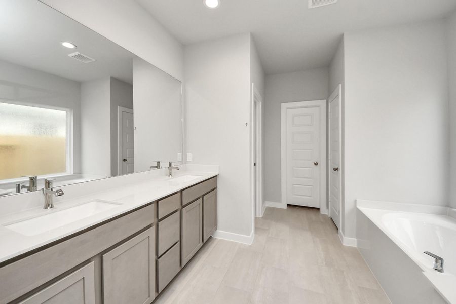 Escape to a spa-like oasis in this primary bathroom. Enjoy a walk-in shower with tile surround, a separate garden tub with custom detailing, and an elegant vanity featuring light countertops, modern hardware, and beautiful recessed lights. Experience luxury and relaxation in every detail. Sample photo of completed home with similar floor plan. Actual colors and selections may vary. Escape to a spa-like oasis in this primary bathroom. Enjoy a walk-in shower with tile surround, a separate garden tub with custom detailing, and an elegant vanity featuring light countertops, modern hardware, and beautiful recessed lights. Experience luxury and relaxation in every detail. Sample photo of completed home with similar floor plan. Actual colors and selections may vary.