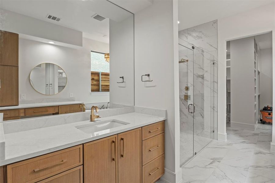 Bathroom featuring vanity, a marble finish shower, and light marble finish floors Bathroom featuring vanity, a marble finish shower, and light marble finish floors
