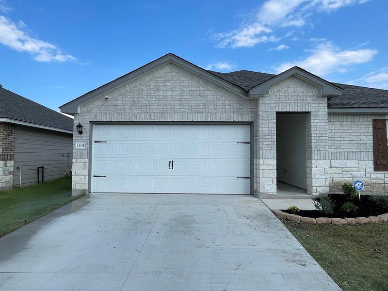 Ranch-style home with concrete driveway, an attached garage, a shingled roof, and brick siding