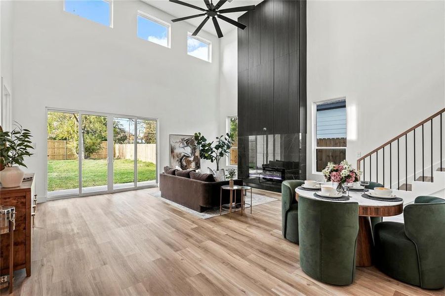 Two-story living area featuring wood-finish flooring, a contemporary fireplace with a dark surround, and a ceiling fan