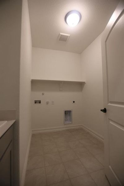 Utility room featuring ceramic tile flooring, a built-in wall shelf, a flush mount ceiling light, and essential appliance hookups