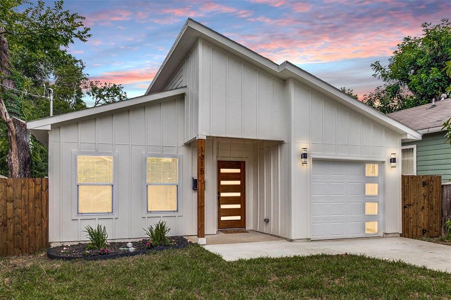 View of front of property with a garage and a yard