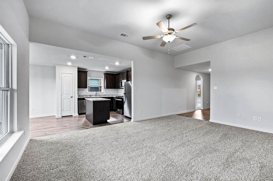 Unfurnished living room with sink, ceiling fan, and carpet flooring