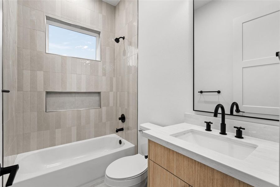 Thoughtfully finished with textured tile and a streamlined vanity, this guest bath balances function and understated design.