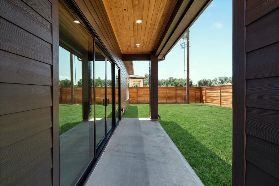 The covered patio creates a true outdoor extension of the home, framed by warm tongue-and-groove wood soffits and opening to an expansive 30' x 60' backyard with room to create a future pool or outdoor retreat.