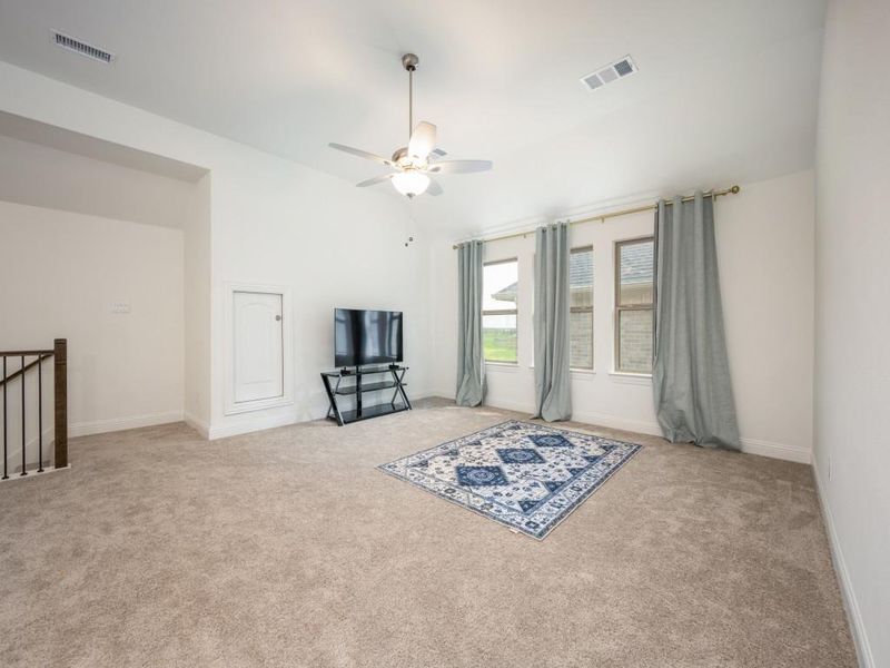 Unfurnished room with carpet flooring, ceiling fan, vaulted ceiling, and visible vents